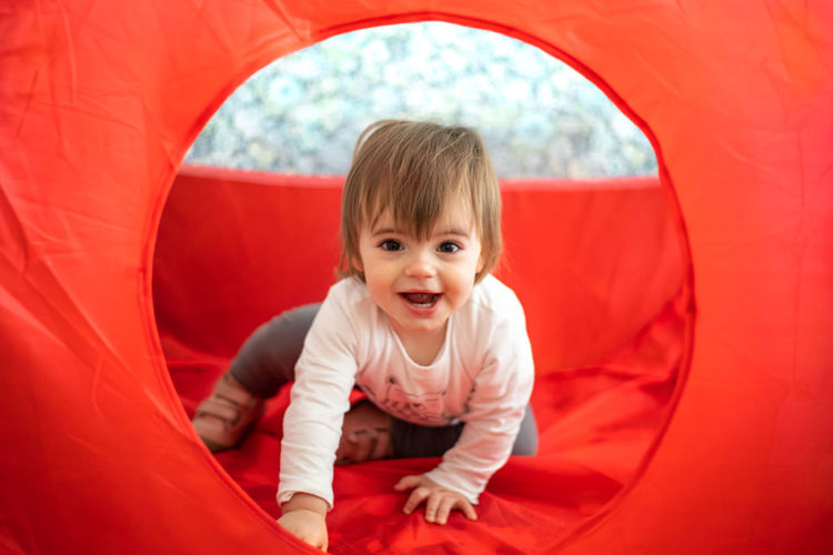 Portrait of cute baby girl sitting on red tent