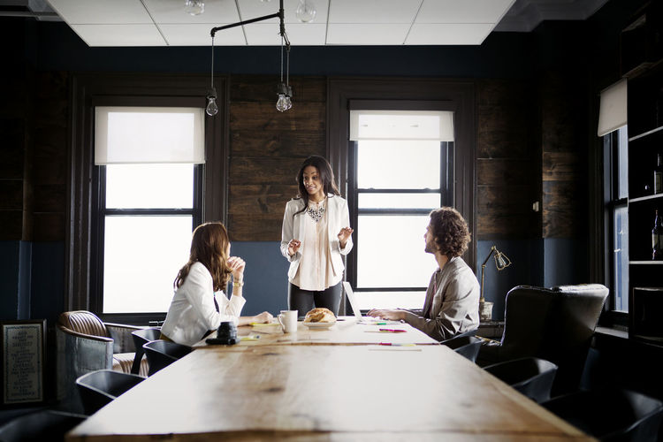 Colleagues looking at businesswoman explaining in office