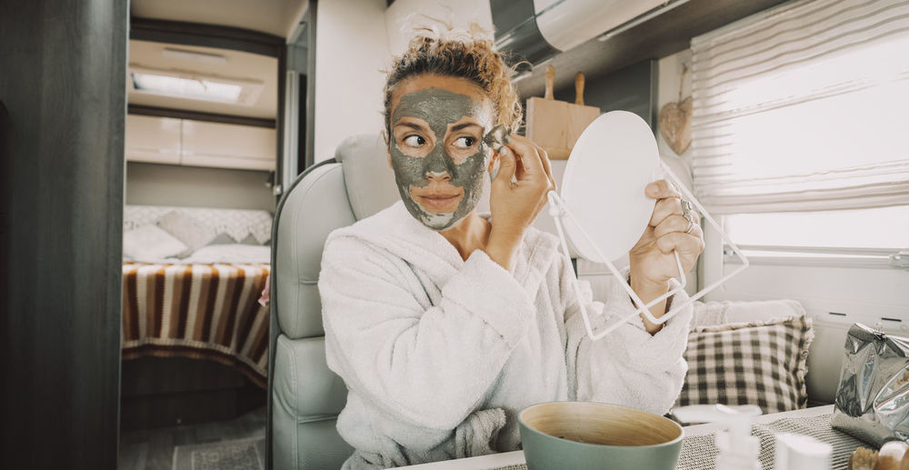 Woman applying face mask on face