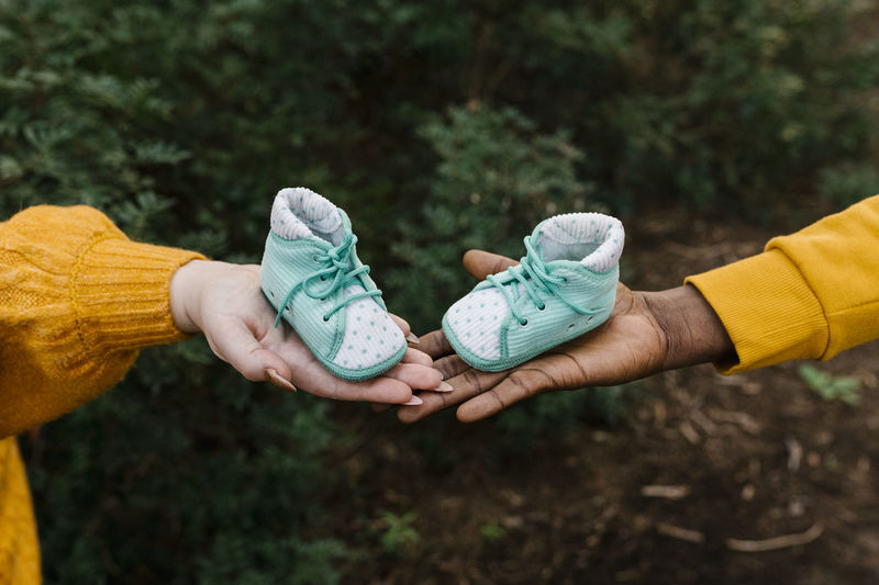 Close-up of couple holding baby booties at forest
