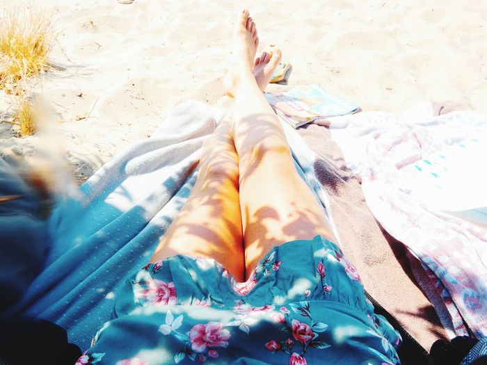 Low section of woman standing on sand at beach
