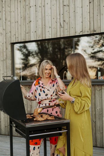 Female friends drinking wine and barbecuing meat