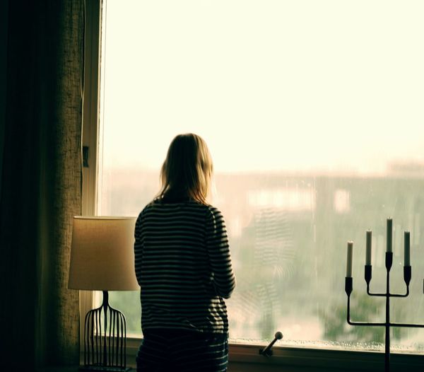Rear view of woman standing by window
