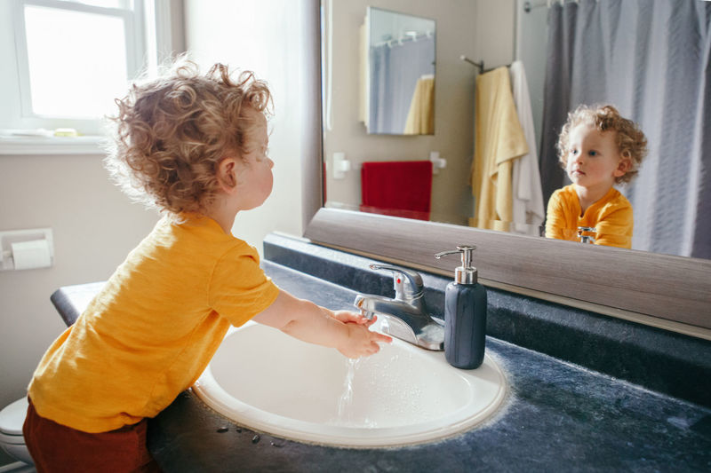 Little caucasian boy toddler washing hands in bathroom at home. health hygiene and morning routine 
