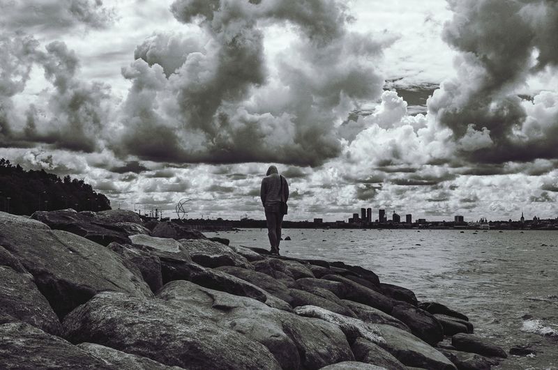 Rear view of man standing on rocks at beach