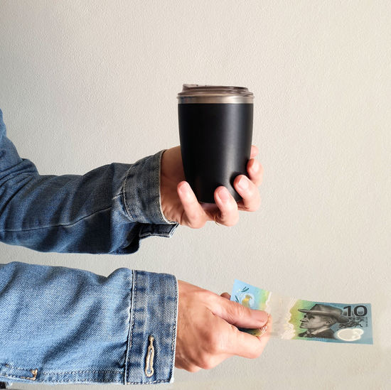 Female hand holding reuseable coffee cup with australian currency