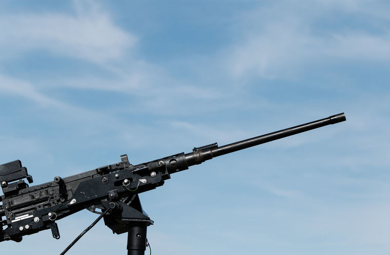 Low angle view of machine gun against blue sky