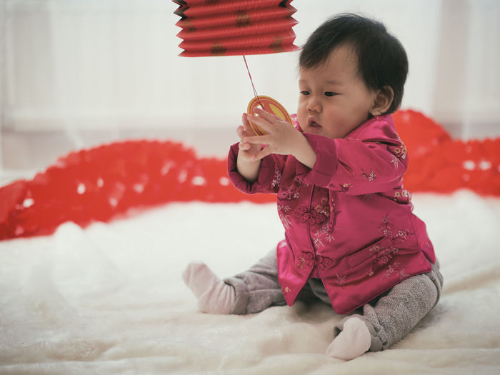 Baby girl playing chinese lantern on bed