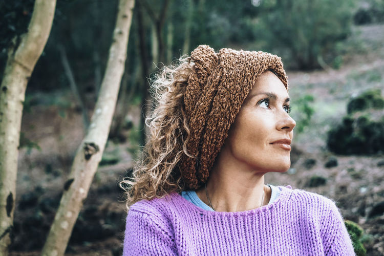 Portrait of young woman standing against trees