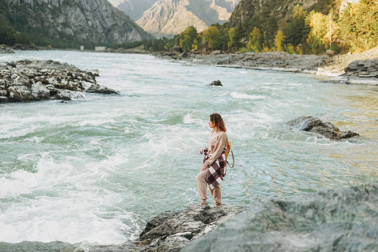 Young woman traveller in casual with backpack on mountain river on sunset