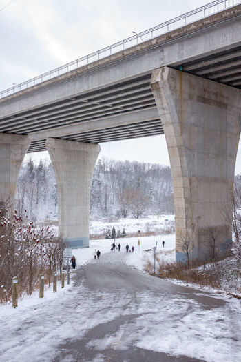 Bridge over snow covered road against sky