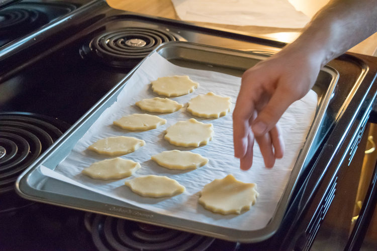 Cropped image of hand placing cookies on baking sheet