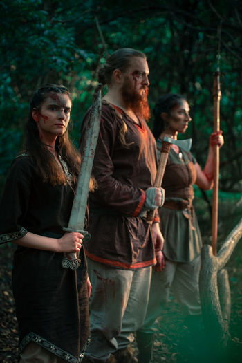 Male and females injured warriors with axe sword and spear for fight against opponent on historical reenactment in woods