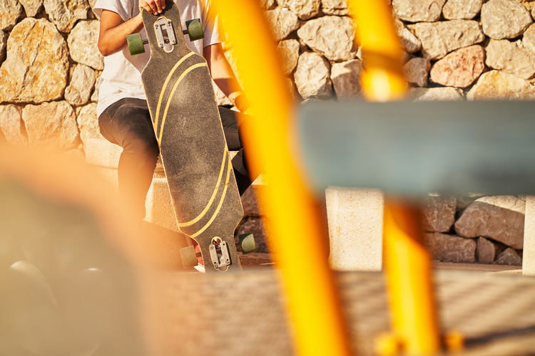 Low section of man with skateboard sitting outdoors