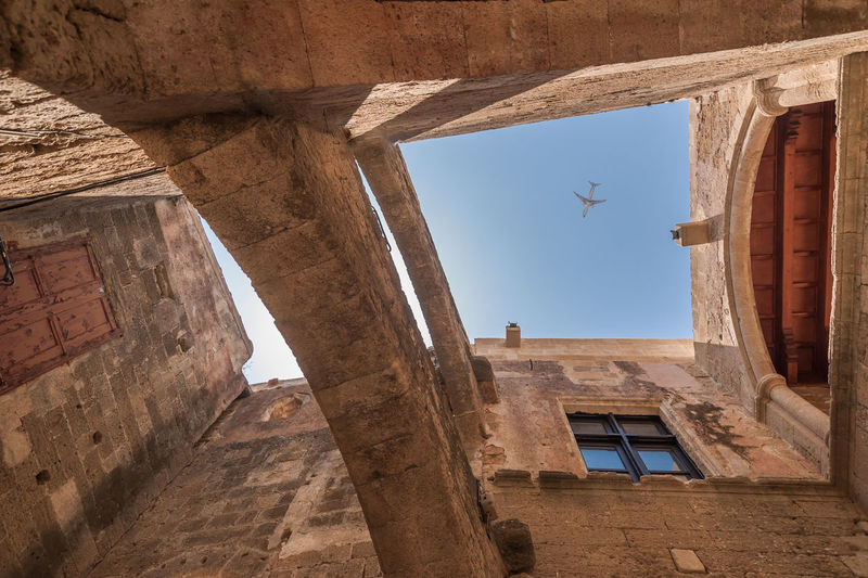 Airplane above old medieval masonry building in rhodes downtown on greek island of rhodes.