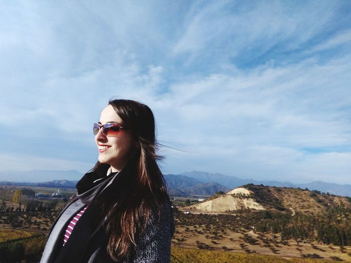 Beautiful young woman wearing sunglasses standing on mountain against sky