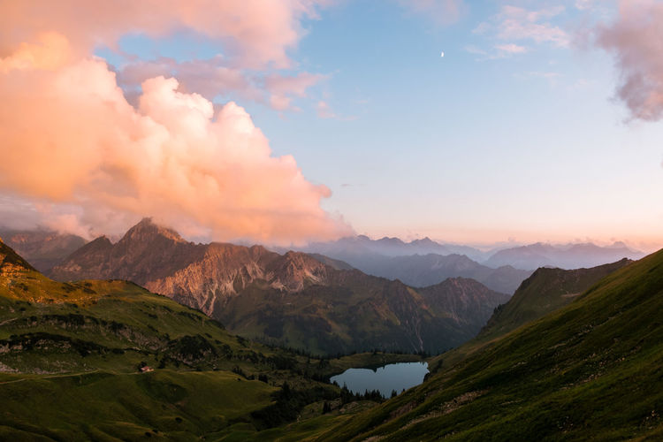Scenic view of lake and mountains against cloudy sky