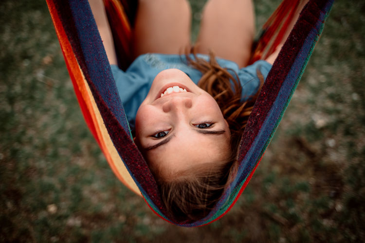 High angle portrait of smiling girl lying on hammock