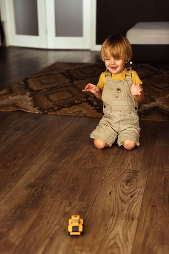 Cute boy sitting on hardwood floor at home