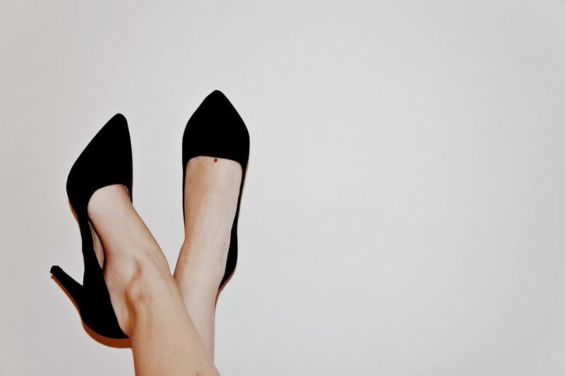 Low section of woman wearing high heels against white background