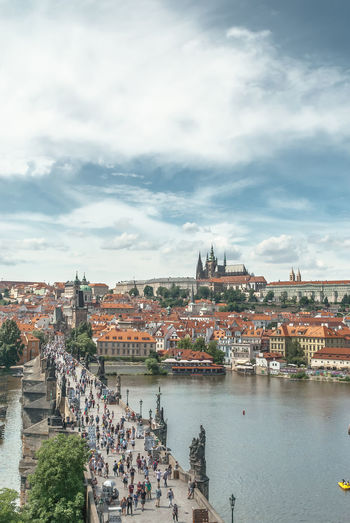 High angle view of people on charles bridge over vltava river against cloudy sky