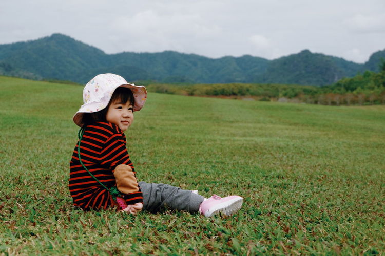 Smiling baby girl sitting on grassy field