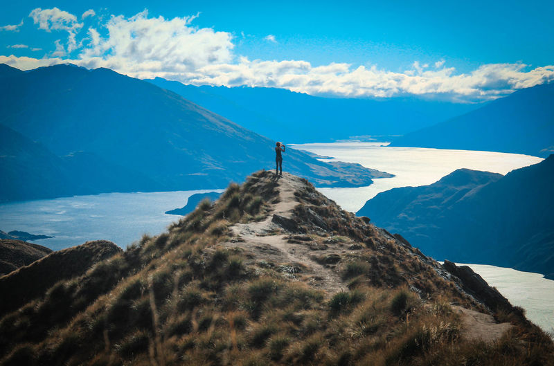 Woman standing on mountain against blue sky