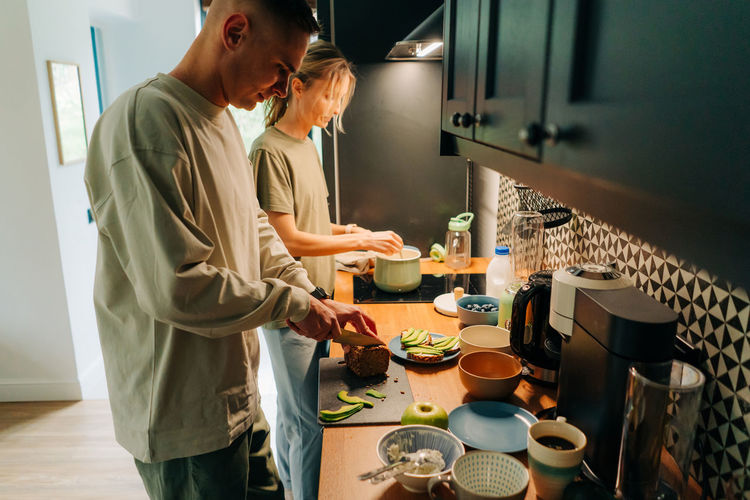 A woman and her boyfriend cook breakfast together in the home kitchen.