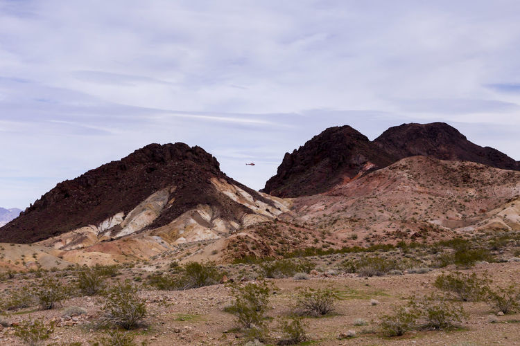 Helicopter seen flying between two colourful hills near lake mead in the boulder city area