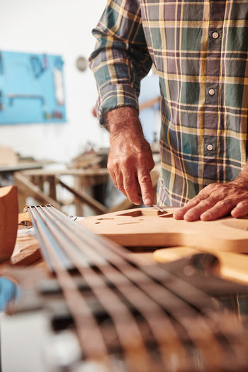 Midsection of man working on guitar over table