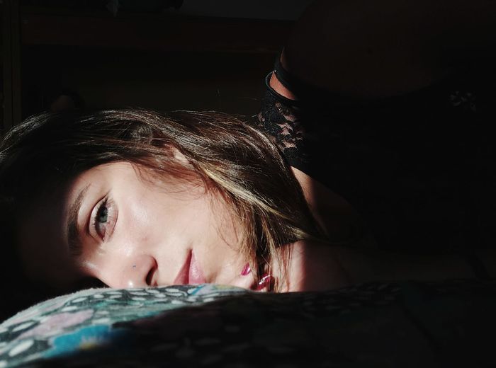 Close-up portrait of woman lying on bed at home