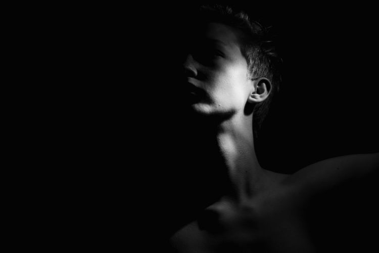 Close-up of shirtless boy against black background