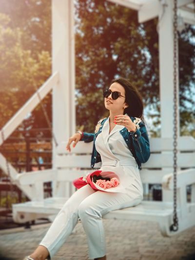 Young woman wearing sunglasses sitting on swing