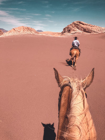 First person view of a young male horseback riding through desert