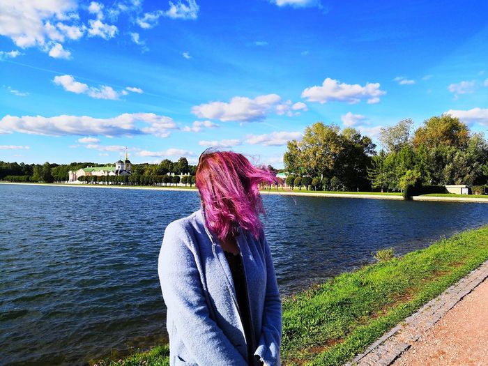 Woman standing by lake against blue sky