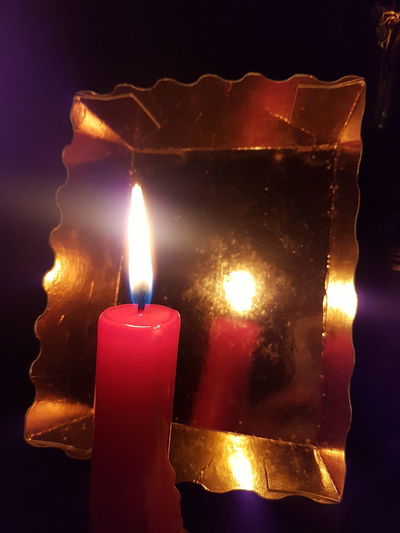 Close-up of burning candles on glass