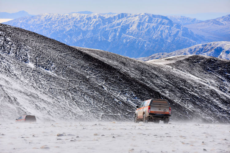 Car on snow covered field by mountains