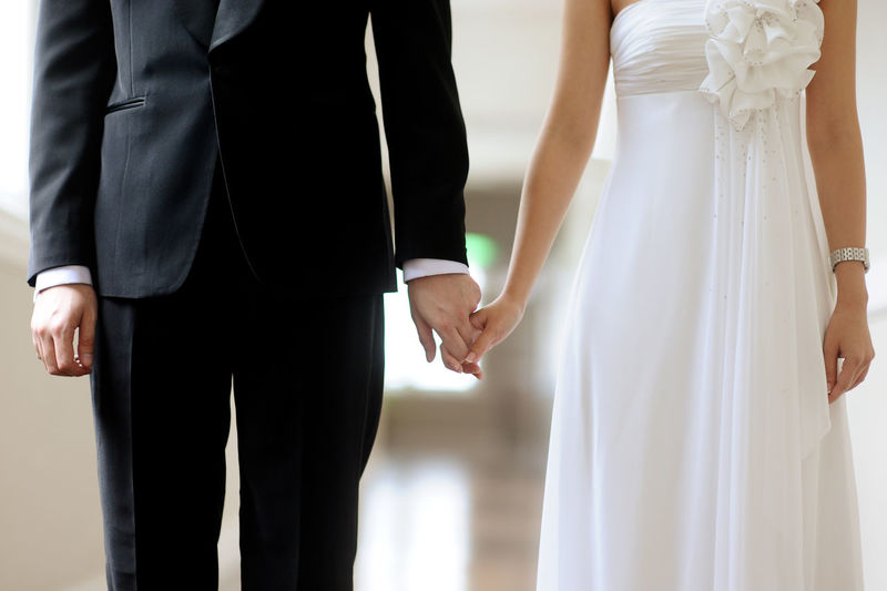 Midsection of bride and groom holding hands during weeding