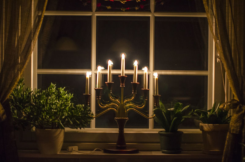Illuminated candlestick holder on window sill