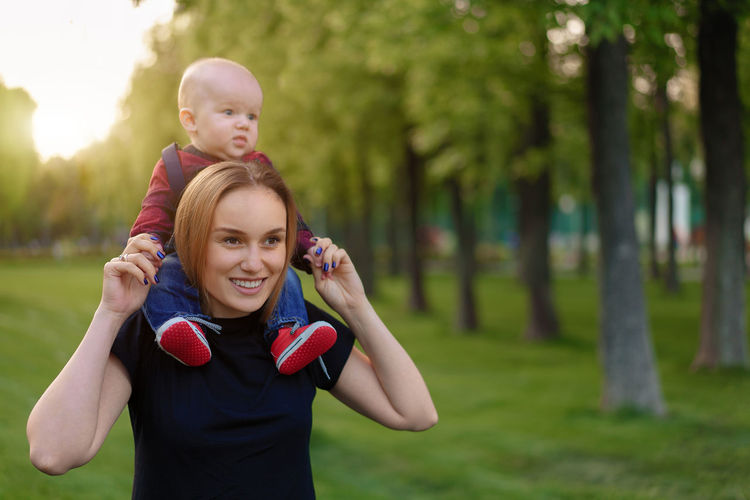 Smiling mother looking away while piggybacking son in park