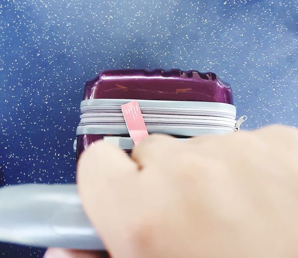 Close-up of hand holding suitcase