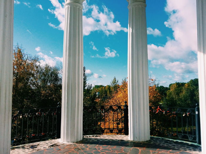 Columns by autumn trees against blue sky