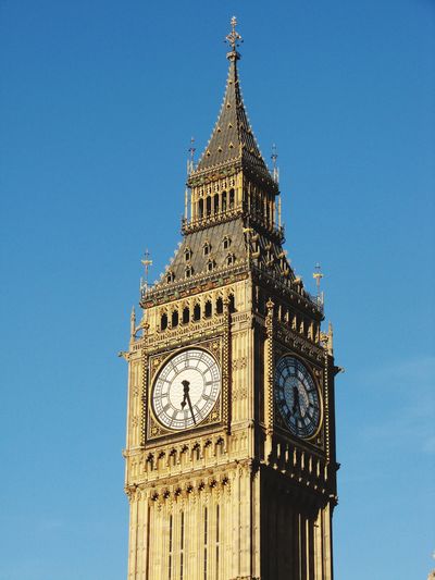 Low angle view of clock tower against clear blue sky