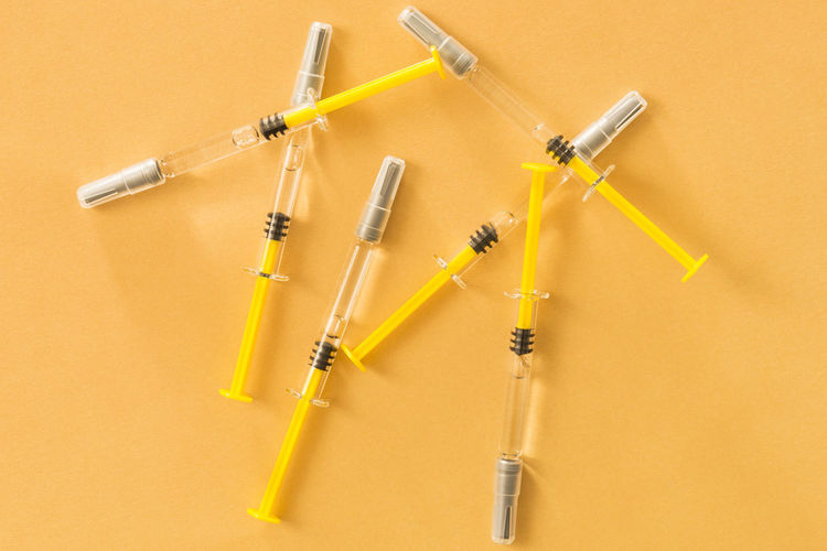 Close-up of syringe against yellow background