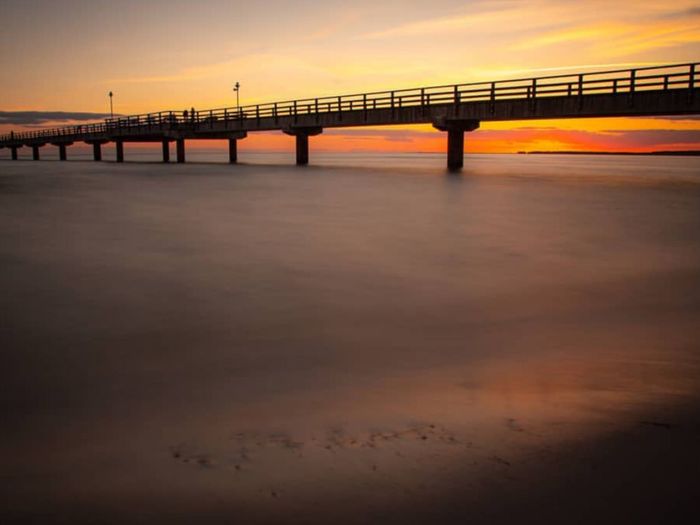 Pier over sea against sky during sunset