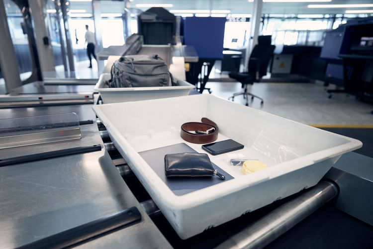 Personal items, liquids, and laptop in container at airport security check before flight.