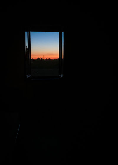 Silhouette landscape seen through window at sunset