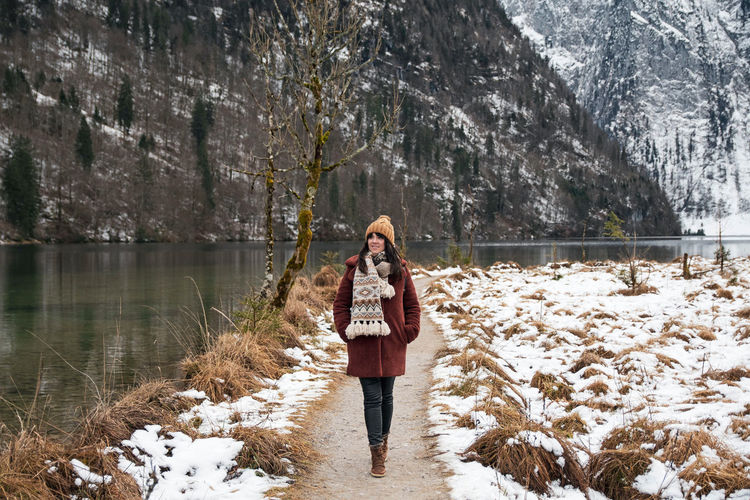 Young woman walking on a path by a lake. winter, snow, cold weather.