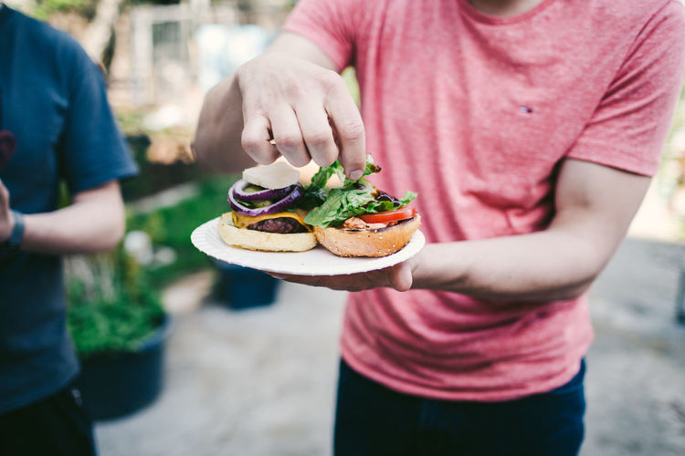 Midsection of man holding burger in plate