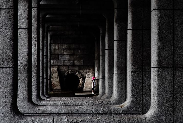 Girl standing in corridor along pillars
